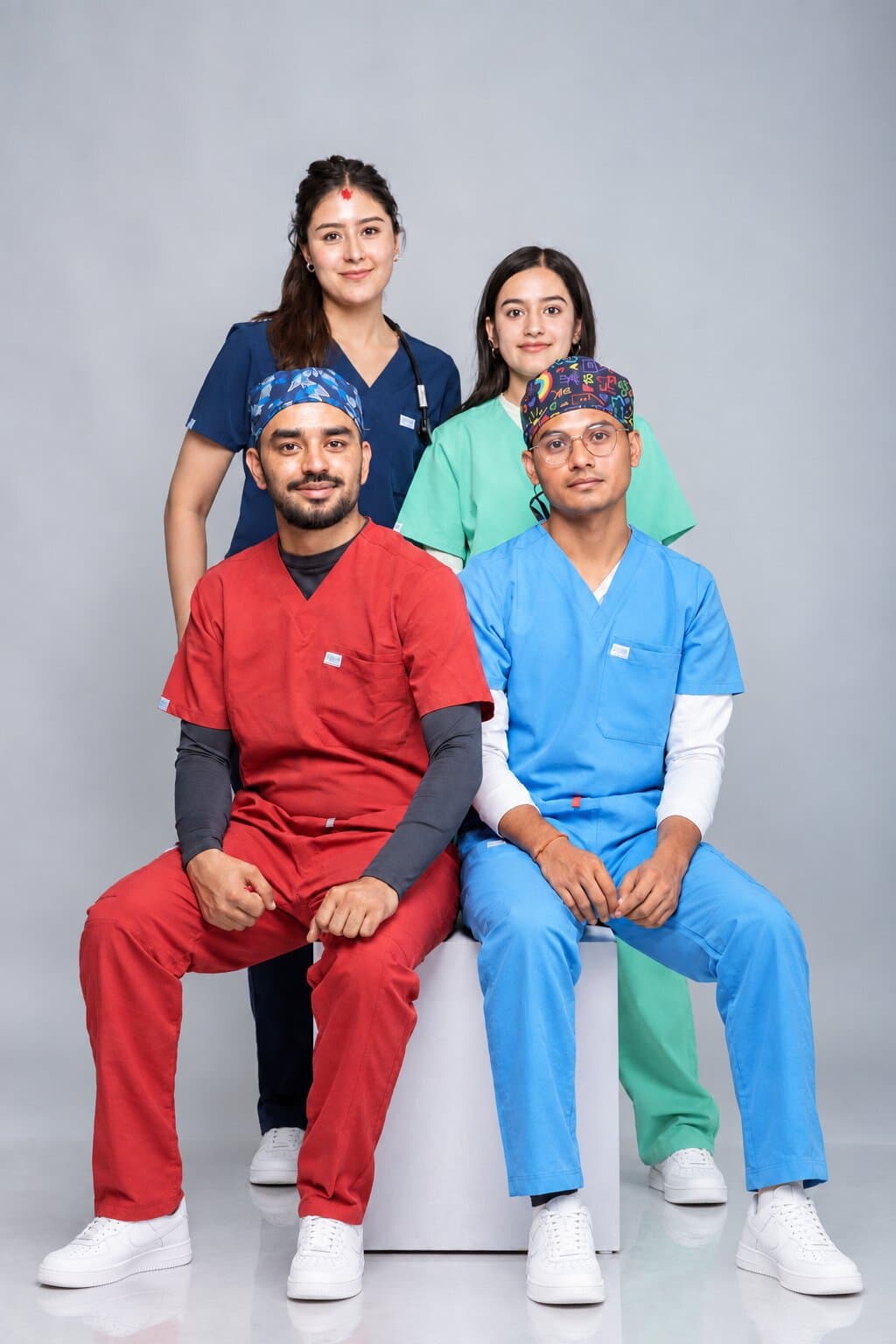 Four healthcare workers in navy, mint, red and ceil blue Medisewa scrubs